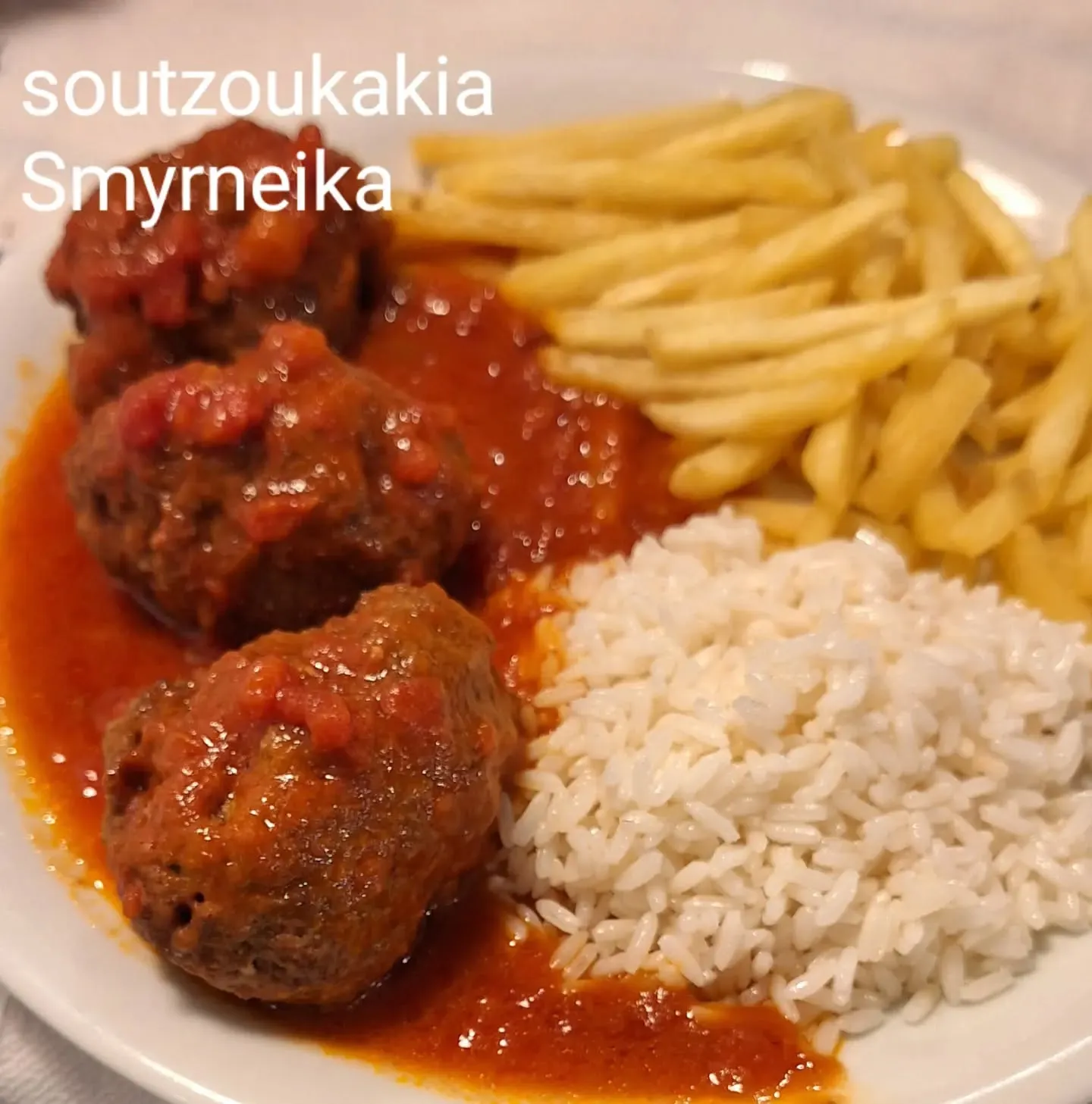 Prato de soutzoukakia ao molho de tomate com arroz e batata frita