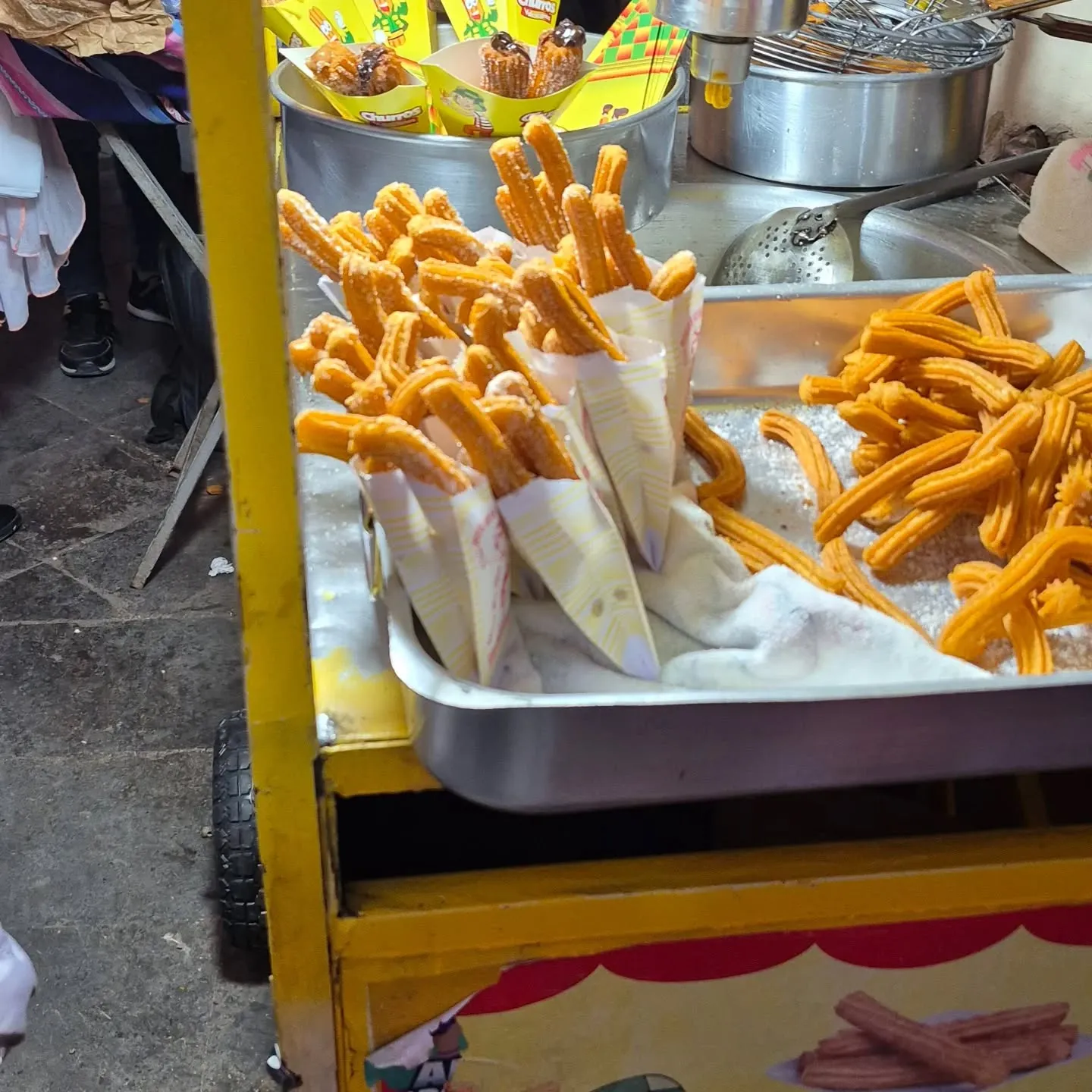 Churros em cones de papel num carrinho de rua