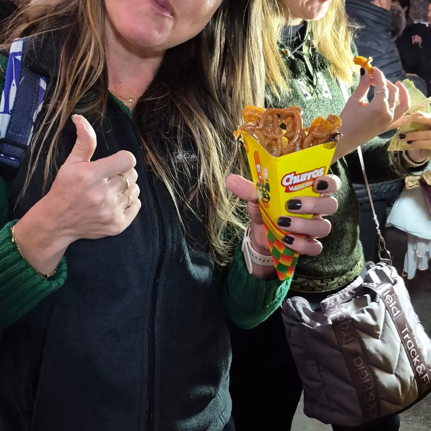Mulher fazendo sinal de positivo com um cone de churros na mão