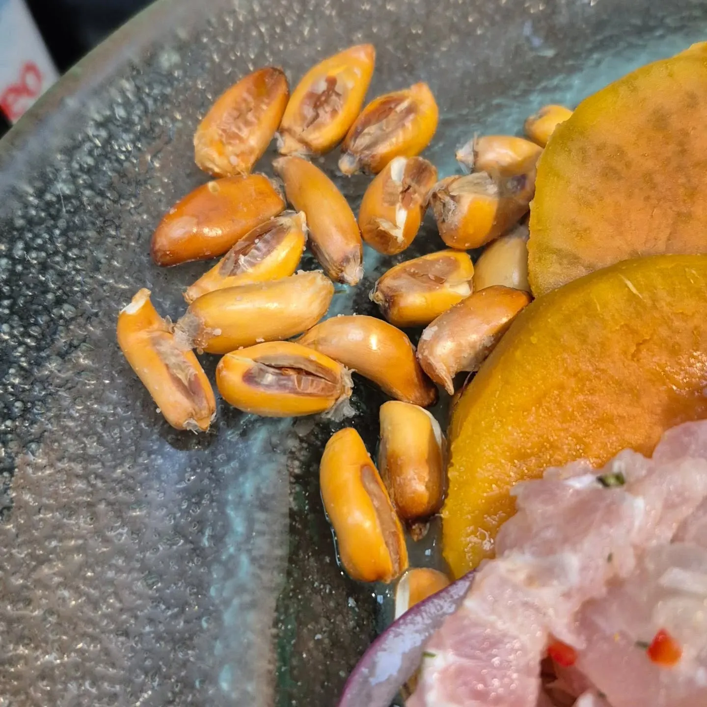 Cancha, milho torrado, e fatias de batata-doce ao lado do ceviche