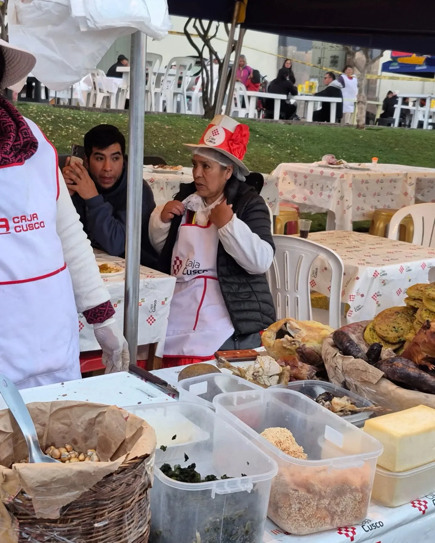 Barraca do festival com uma cozinheira de chapéu vermelho e pratos típicos à mesa
