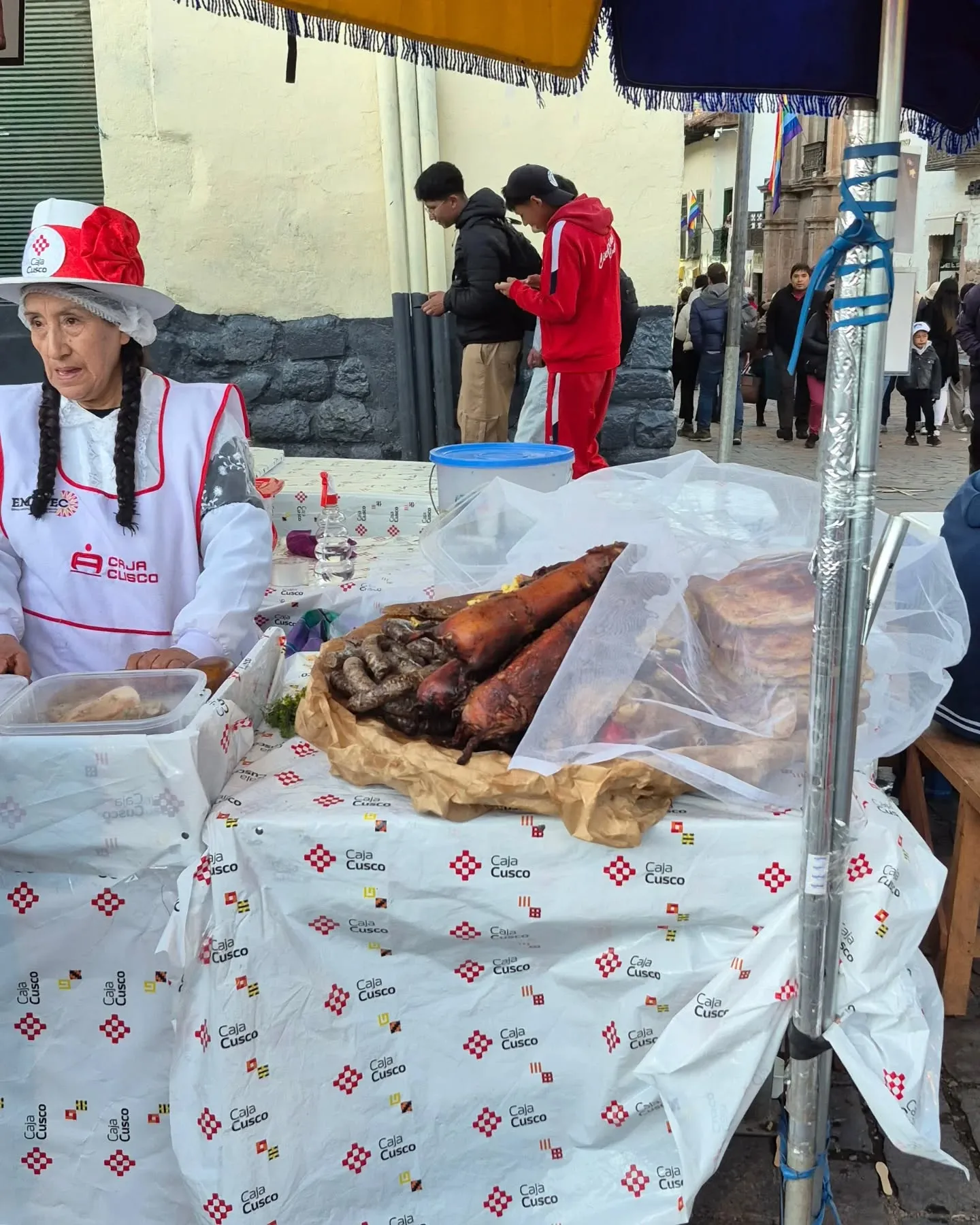 Cozinheira idosa de chapéu ao lado da sua mesa de pratos do Chiriuchu