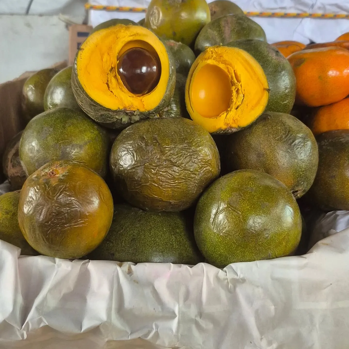 Lúcumas inteiras e uma partida ao meio, mostrando a polpa amarela e o caroço